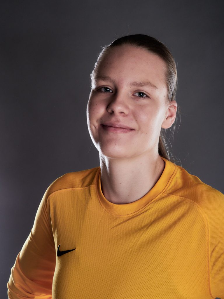 Wiktoria, gardienne de football, en portrait studio, vêtue d’un maillot jaune de gardienne.