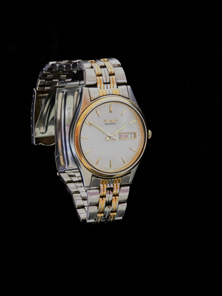 Montre Seiko Quartz bicolore (acier et or) avec cadran blanc et dateur, photographiée sur fond noir de studio.