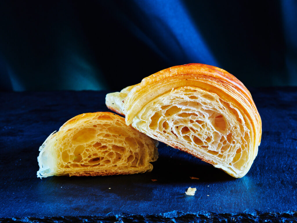 Croissant artisanal coupé en deux montrant le feuilletage parfait - Photographie culinaire Beauchamp