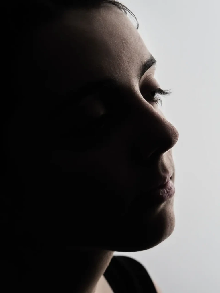Gros plan sur un profil de visage en clair-obscur, fond clair.
