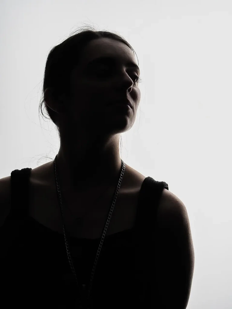 Portrait en silhouette d'une femme sur fond clair, contre-jour marqué.
