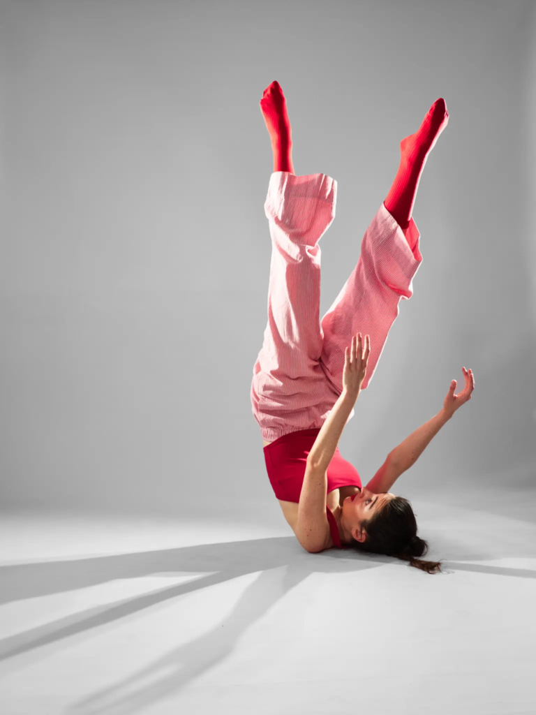 Danseuse en inversion, jambes tendues vers le ciel, tenue rouge