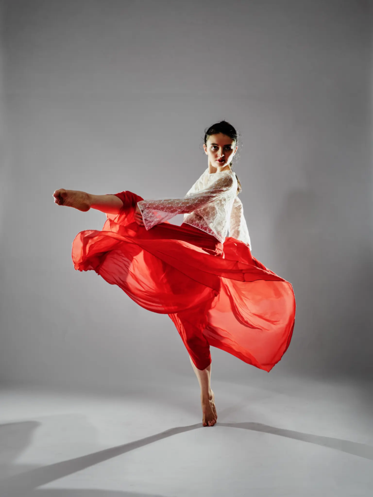 Danseuse en jupe rouge et haut dentelle blanche, saut aérien