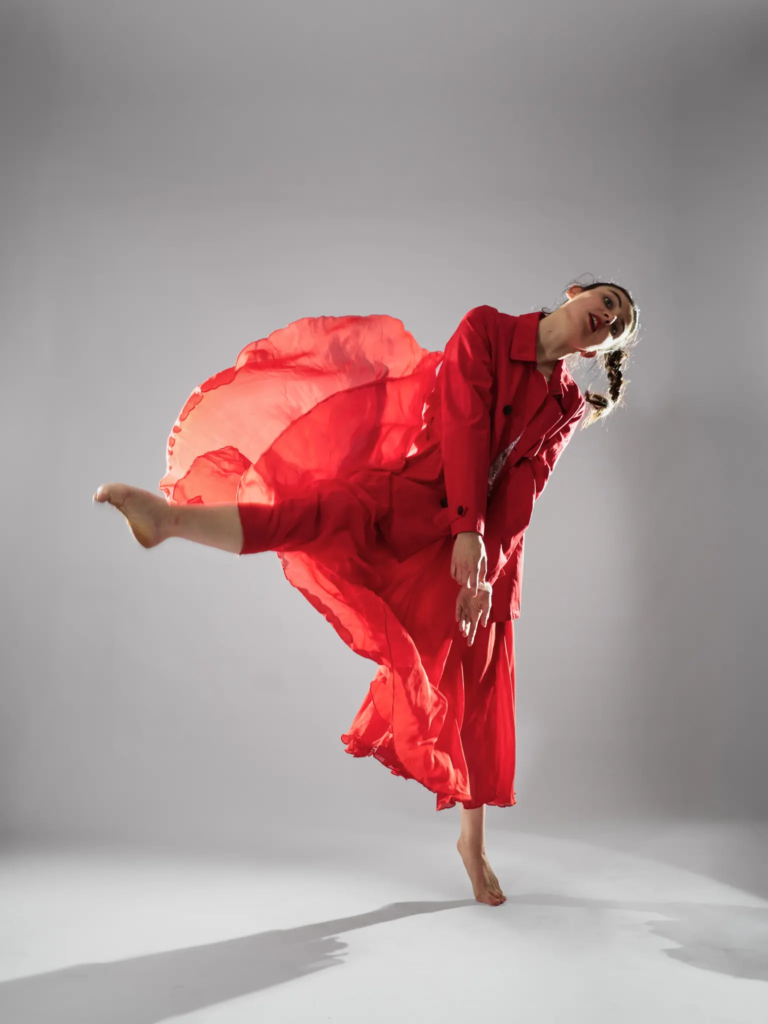 Danseuse en saut, jupe rouge en mouvement, regard caméra