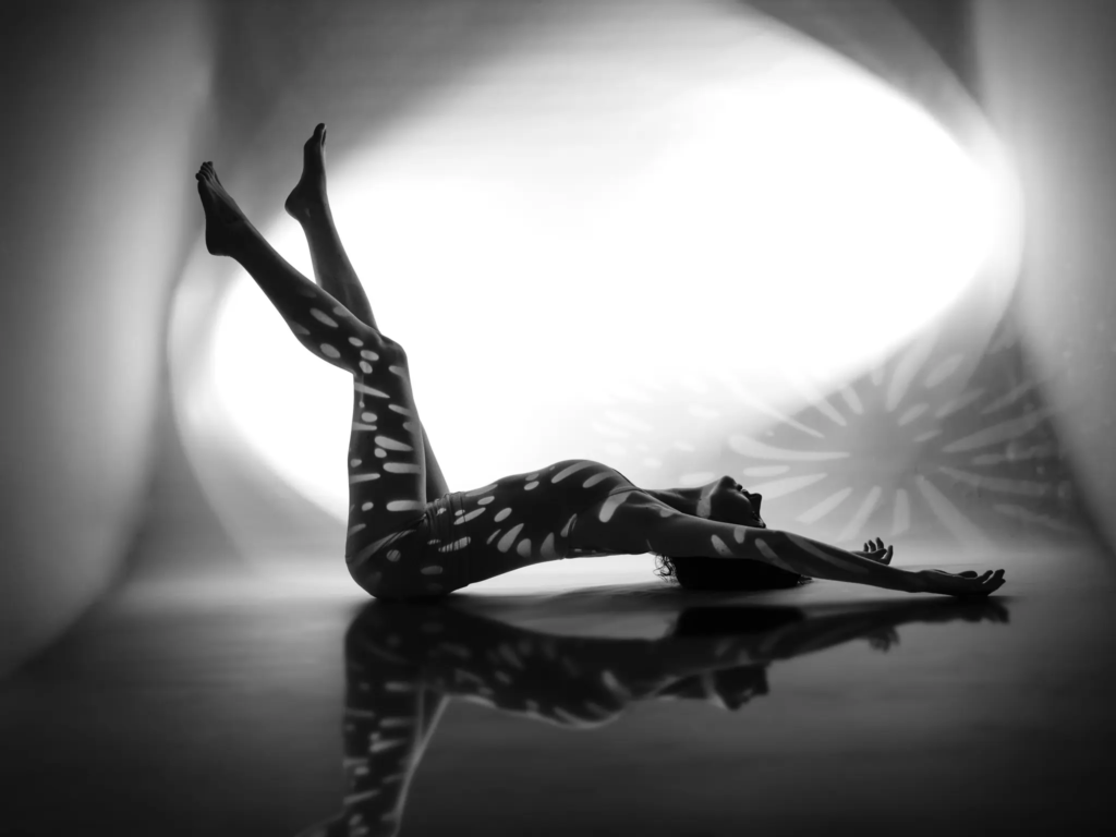 Danseuse allongée jambes levées, motif de lumière et reflet au sol