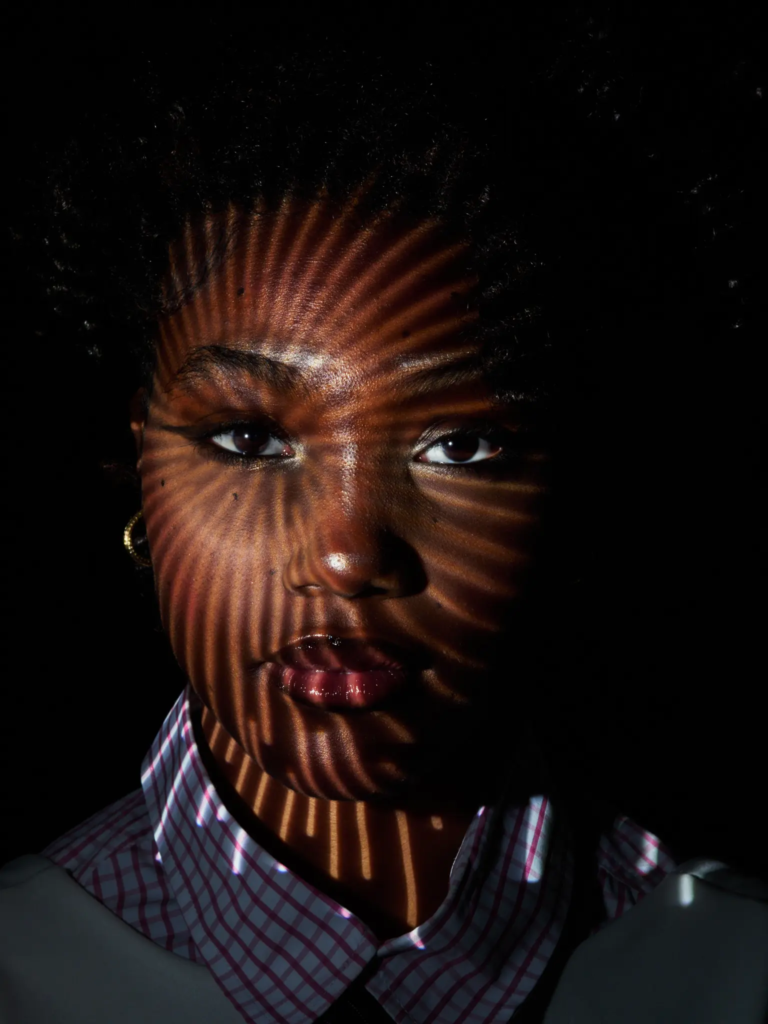 Visage sculpté par un motif de lumière projetée façon gobo, portrait studio noir et blanc