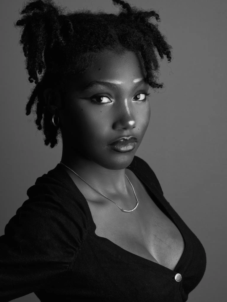 Portrait noir et blanc, regard de biais, cardigan noir et bijoux